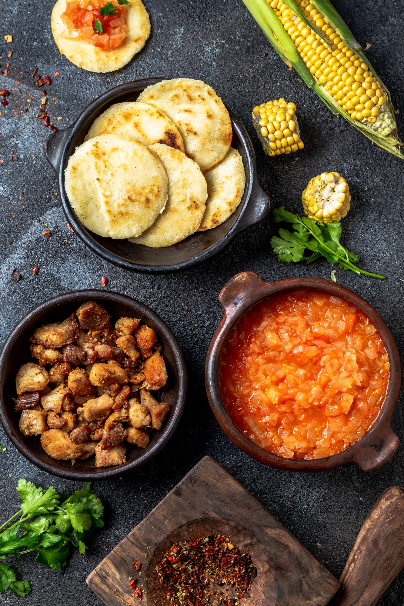 COLOMBIAN traditional food. Chicharron, maize arepas with tomato and onion sauce. Top view